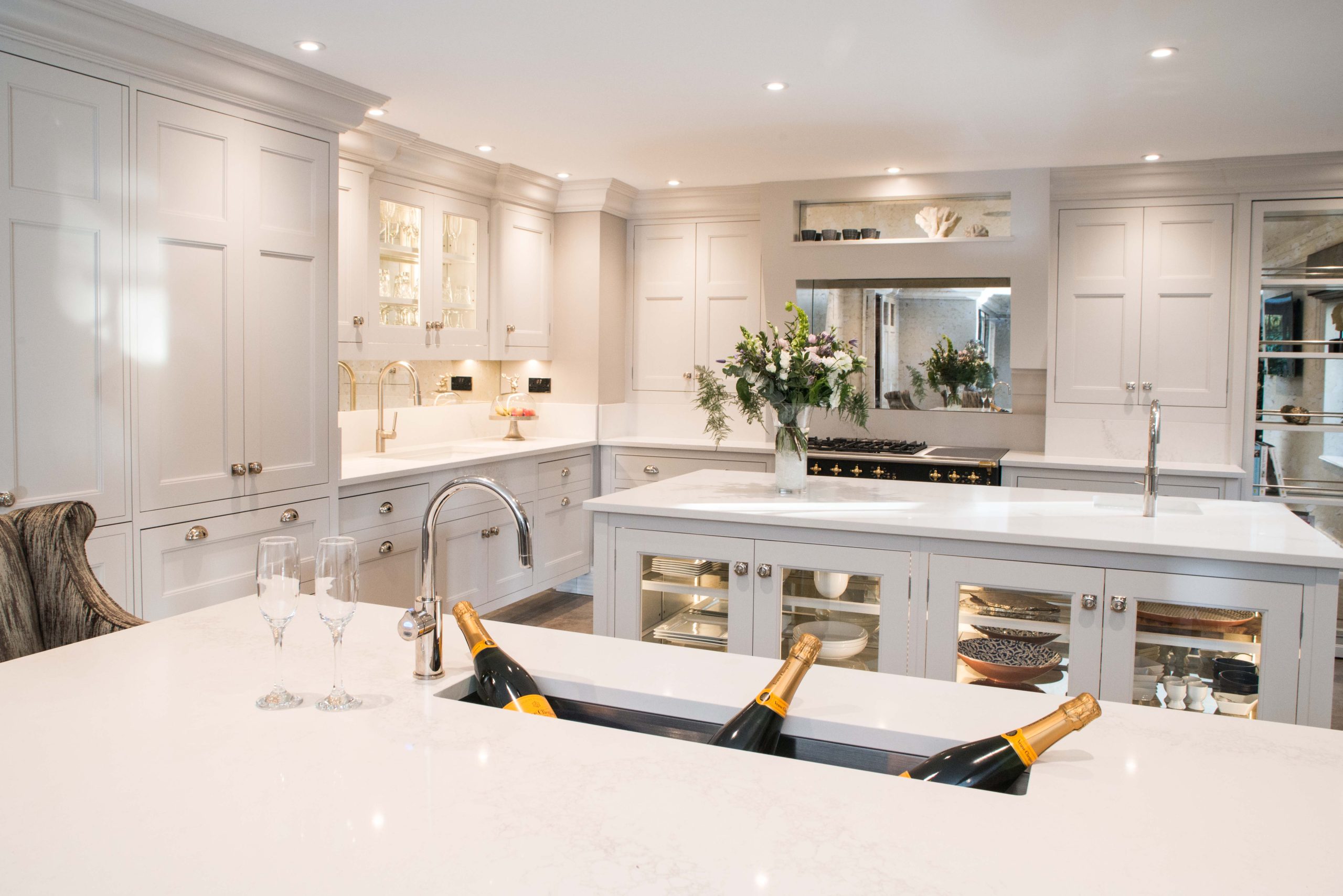 Grey shaker kitchen with dual islands, integrated wine chiller, mirrored splashback and brass hardware