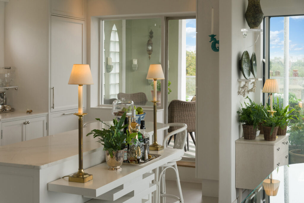 White panelled kitchen nook with round porthole window, open display shelving and integrated tall fridge freezer