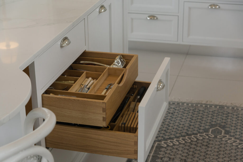 White panelled kitchen nook with round porthole window, open display shelving and integrated tall fridge freezer