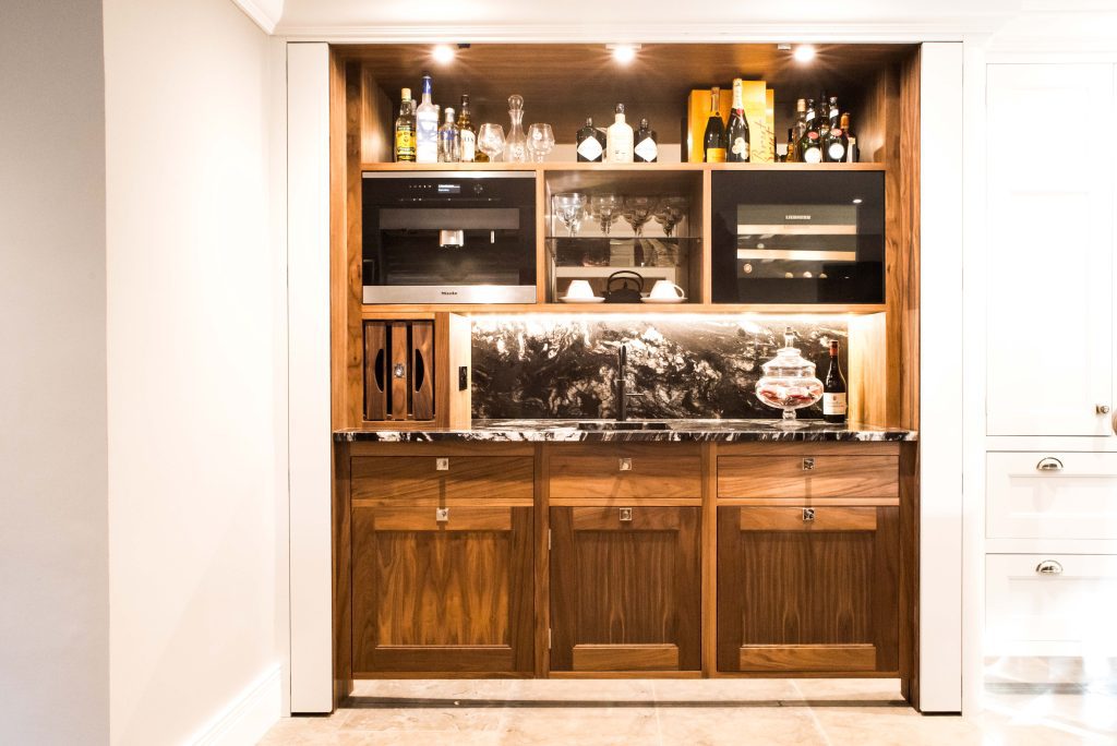 Fitted bar area with a slide-and-hide pocket door revealing glassware storage