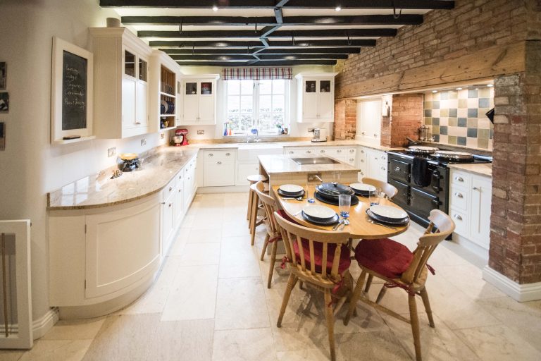 Farmhouse-style kitchen with wooden beams, a dining table and cream cabinetry