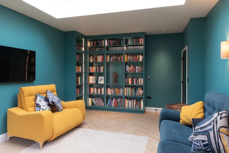 Teal library with built-in bookshelves and a yellow armchair