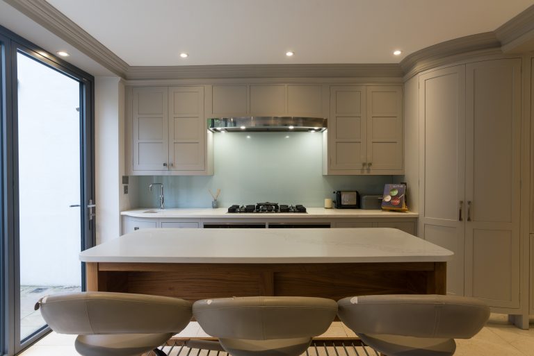 Kitchen with pale cabinetry, hob and glass splashback