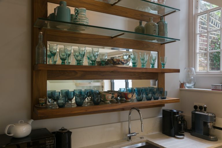 Glass-shelved display cabinet with ceramics, teal glassware and integrated lighting