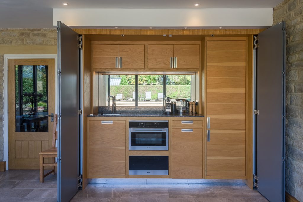 Kitchen with light oak cabinetry beneath a window