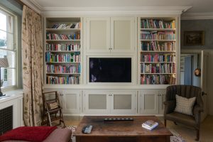 Built-in bookshelves and cabinetry with an integrated wall-mounted TV, different angle