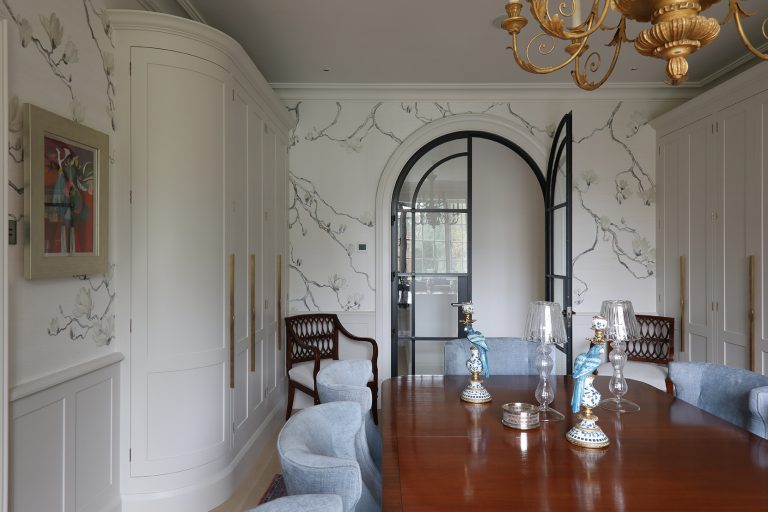 Dining room with a black arched doorway and upholstered chairs